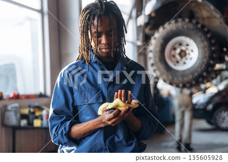 Cleaning the hands after work. Male mechanic is with car in garage 135605928