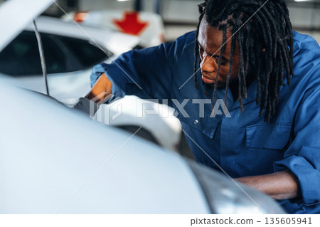 Fixing the automobile, under the hood. Male mechanic is with car in garage 135605941