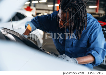 Fixing the automobile, under the hood. Male mechanic is with car in garage Fixing the automobile, under the hood. Male mechanic is with car in garage 135605942