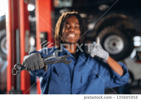 Showing the wrenches. Male mechanic is with car in garage 135605958
