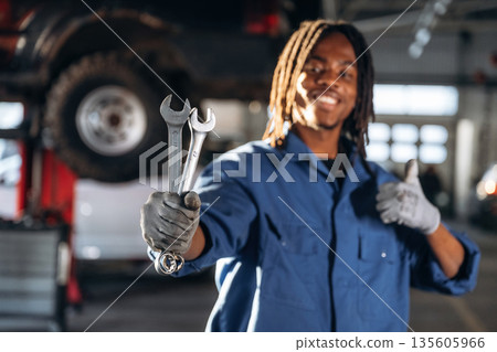 Tools in hands. Male mechanic is with car in garage Tools in hands. Male mechanic is with car in garage 135605966