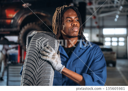 Time to move and change tire. Male mechanic is with car in garage Time to move and change tire. Male mechanic is with car in garage 135605981