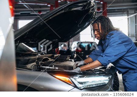 Front part, hood is opened, fixing the automobile. Male mechanic is with car in garage 135606024