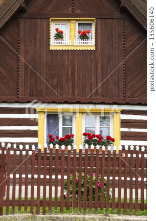 Traditional wooden house facade with red geraniums, Czechia Traditional wooden house facade with red geraniums, Czechia 135606140