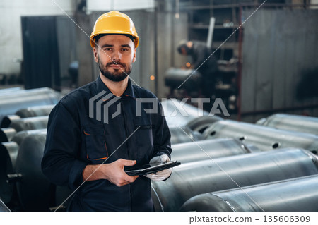 Checking information in digital tablet. Man is working in the factory Checking information in digital tablet. Man is working in the factory 135606309