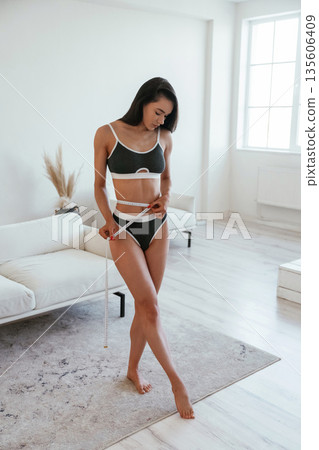 Diet conception, measuring tape. Young woman with slim body type is indoors Diet conception, measuring tape. Young woman with slim body type is indoors 135606409