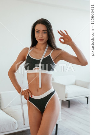 Diet conception, measuring tape. Young woman with slim body type is indoors Diet conception, measuring tape. Young woman with slim body type is indoors 135606411