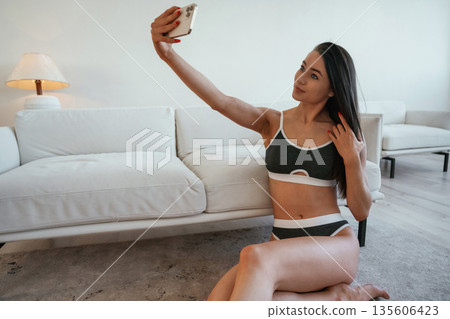 Leaning on the sofa. Young woman with slim body type is indoors 135606423