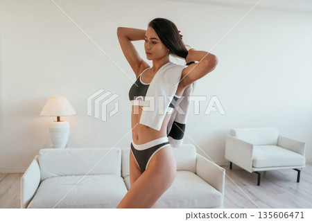 Towel on the neck. Young woman with slim body type is indoors Towel on the neck. Young woman with slim body type is indoors 135606471