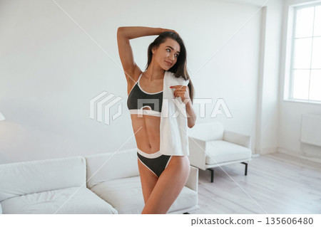 Daytime, standing, with towel. Young woman with slim body type is indoors Daytime, standing, with towel. Young woman with slim body type is indoors 135606480