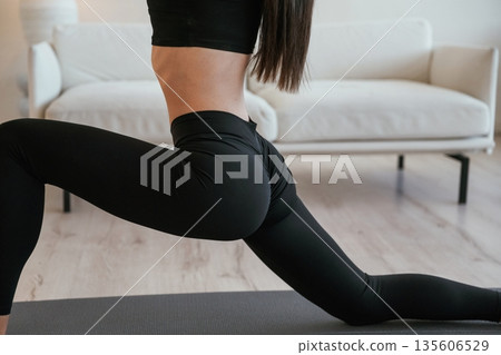 Focused close up view, doing yoga. Young woman with slim body type is indoors Focused close up view, doing yoga. Young woman with slim body type is indoors 135606529