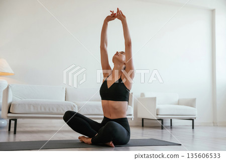 Warming up exercises. Young woman with slim body type is indoors Warming up exercises. Young woman with slim body type is indoors 135606533
