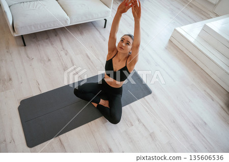 Warming up exercises. Young woman with slim body type is indoors 135606536