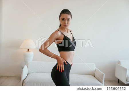 Just standing and posing. Young woman with slim body type is indoors 135606552
