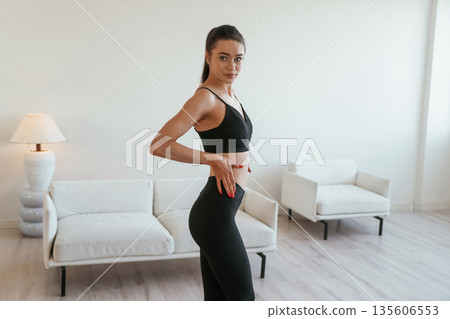 Just standing and posing. Young woman with slim body type is indoors Just standing and posing. Young woman with slim body type is indoors 135606553