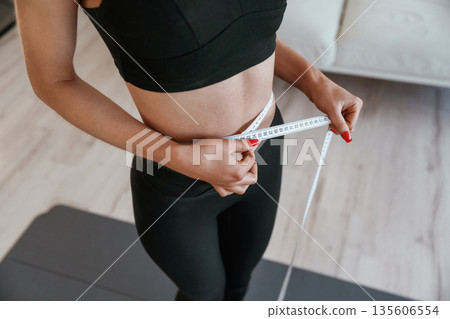 Conception of weight loss, diet. Young woman with slim body type is indoors Conception of weight loss, diet. Young woman with slim body type is indoors 135606554