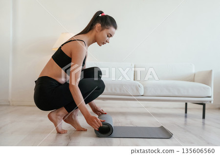 Rolling off the yoga mat. Young woman with slim body type is indoors Rolling off the yoga mat. Young woman with slim body type is indoors 135606560