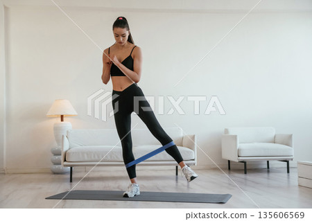 Legs work, stretching. Young woman with slim body type is indoors Legs work, stretching. Young woman with slim body type is indoors 135606569