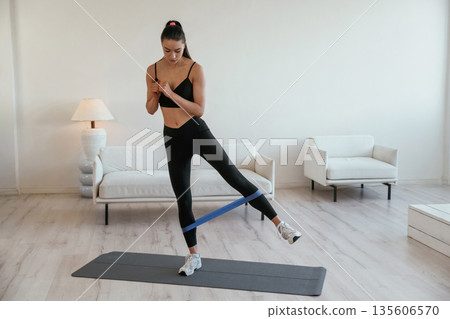 Legs work, stretching. Young woman with slim body type is indoors Legs work, stretching. Young woman with slim body type is indoors 135606570