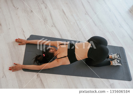 Spine stretching exercise. Young woman with slim body type is indoors 135606584