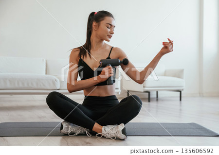 Wireless electric massager. Young woman with slim body type is indoors 135606592
