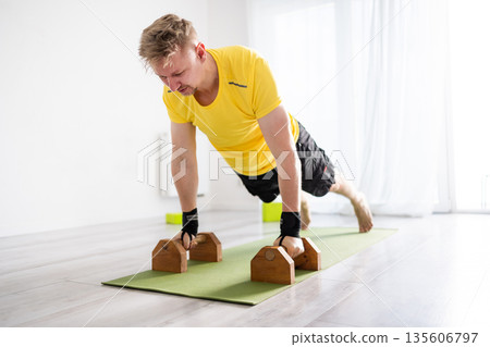 Sporty Man Does Morning Routine Push-Ups At Home Using Floor Dip Bars Sporty Man Does Morning Routine Push-Ups At Home Using Floor Dip Bars 135606797