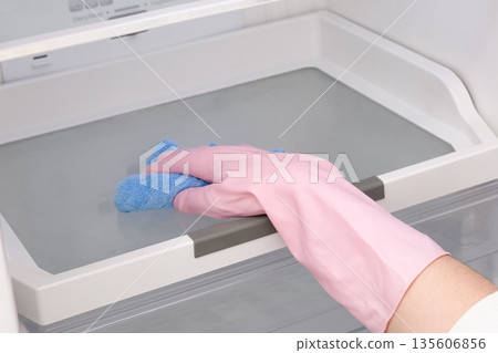 Close-up of a woman's gloved hand wiping down a refrigerator Close-up of a woman's gloved hand wiping down a refrigerator 135606856