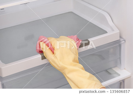 Close-up of a woman's gloved hand wiping down a refrigerator Close-up of a woman's gloved hand wiping down a refrigerator 135606857