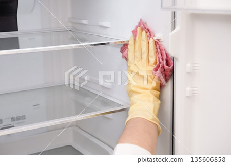Close-up of a woman's gloved hand wiping down a refrigerator Close-up of a woman's gloved hand wiping down a refrigerator 135606858