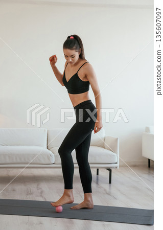 Small massage roller. Young woman with slim body type is indoors 135607097