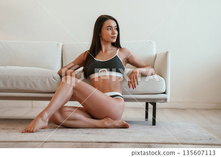 In fitness clothes. Young woman with slim body type is indoors In fitness clothes. Young woman with slim body type is indoors 135607113