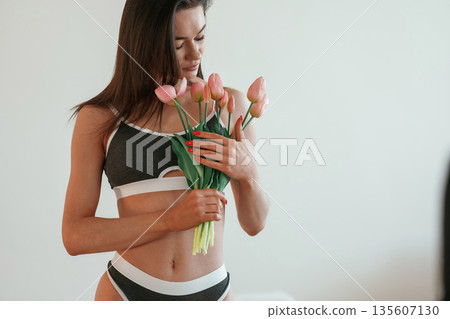 Gift of flowers in hands. Young woman with slim body type is indoors 135607130