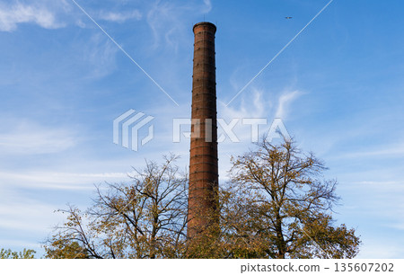 Chimney tower or industrial smokestack. Tower from red brick. Industrial architecture of chimney tower. Brick factory chimney tube. Industrial brick chimney at factory 135607202