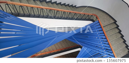 A multi-level staircase interior with bright blue ribbon-like elements. A concept for contemporary architecture and a creative installation in an urban building. A multi-level staircase interior with bright blue ribbon-like elements. A concept for contemporary architecture and a creative installation in an urban building. 135607975