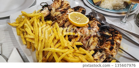 Close-up of fried potatoes and grilled shrimp. Concept of Portuguese traditional food, gastrotourism 135607976