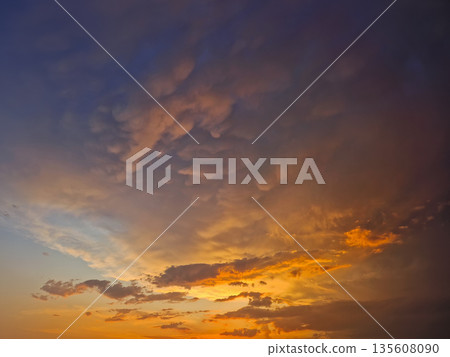Expansive view of a dramatic sunset sky filled with textured mammatus and altocumulus clouds. Breathtaking natural scene with the horizon glowing in fiery orange hues, transiting into deep indigo Expansive view of a dramatic sunset sky filled with textured mammatus and altocumulus clouds. Breathtaking natural scene with the horizon glowing in fiery orange hues, transiting into deep indigo 135608090