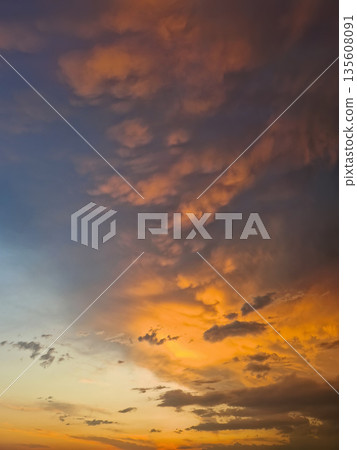 Expansive view of a dramatic sunset sky filled with textured mammatus and altocumulus clouds. Breathtaking natural scene with the horizon glowing in fiery orange hues, transiting into deep indigo Expansive view of a dramatic sunset sky filled with textured mammatus and altocumulus clouds. Breathtaking natural scene with the horizon glowing in fiery orange hues, transiting into deep indigo 135608091
