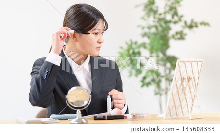 A woman in a recruitment suit straightening her messy hair A woman in a recruitment suit straightening her messy hair 135608333