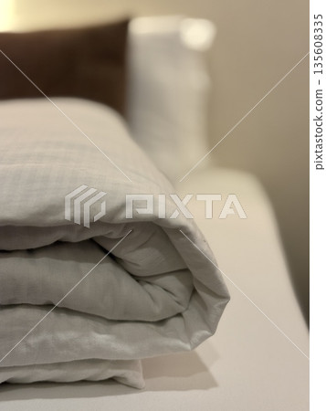 Folded bedding in cozy bedroom setting with neutral tones, perfect for relaxation background 135608335