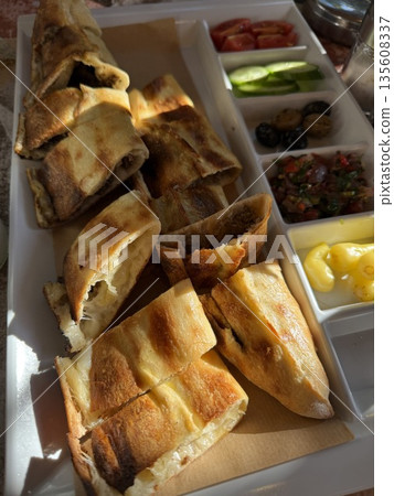 Turkish pide platter with assorted toppings including cheese, olives, vegetables in daylight 135608337