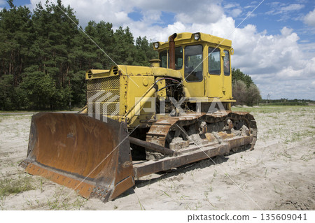 Yellow tractor on the sand on the forest background 135609041