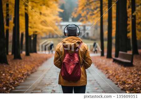 Man with headphones walking in park during autumn time Man with headphones walking in park during autumn time 135609351