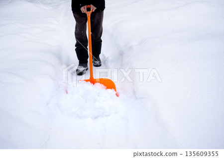 removing a lot of snow by orange plastic shovel removing a lot of snow by orange plastic shovel 135609355
