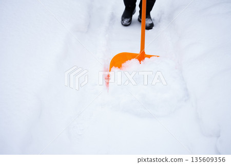 removing a lot of snow by orange plastic shovel after snowfall 135609356