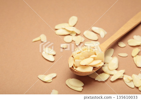 Fresh almond flakes in spoon on brown background. Fresh almond flakes in spoon on brown background. 135610033