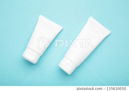 White plastic cosmetic tubes on blue background. Space for text White plastic cosmetic tubes on blue background. Space for text 135610038