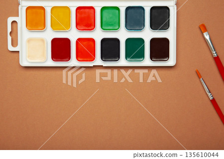 Watercolor paints on brown background. Accessories for drawing and creativity. 135610044