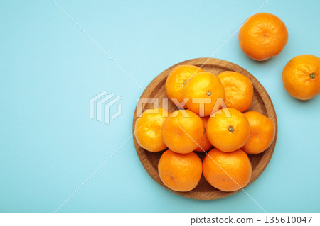 Fresh small tangerine mandarin orange in a plate on blue background. Space for text 135610047