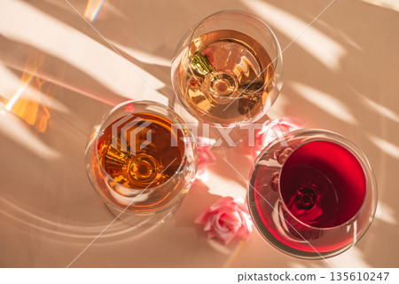 Three Wine Glasses with Rose, White and Red Wine. Romantic Still Life with Warm Light Three Wine Glasses with Rose, White and Red Wine. Romantic Still Life with Warm Light 135610247