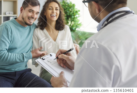 Family doctor sitting with report file with appointment and giving consultation to happy couple 135610401